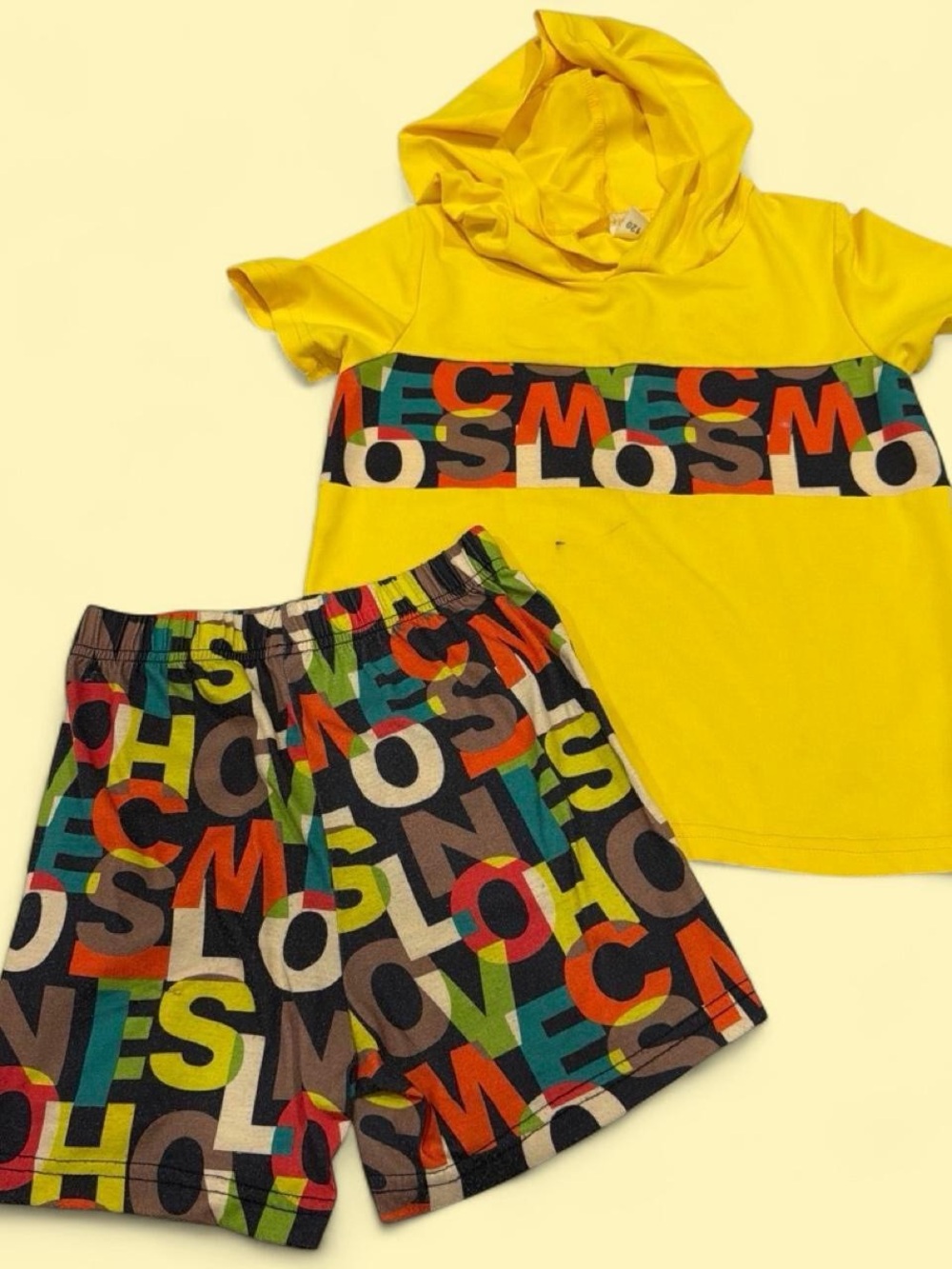 Yellow kids set with multicolored letters spelling 'COMESLO'